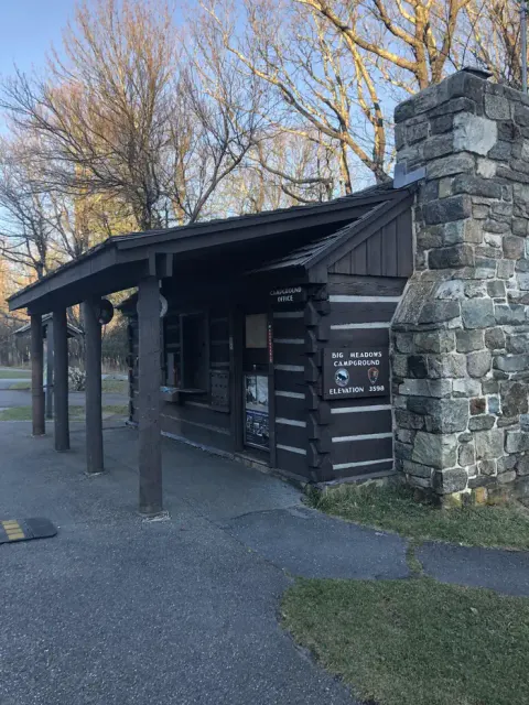 A wooden cabin with stone chimney and signs reading "Big Meadows Campground Elevation 3589" and "Campground Office".