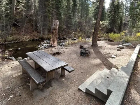 Stairs lead to creekside campsite with picnic table and fire ring.