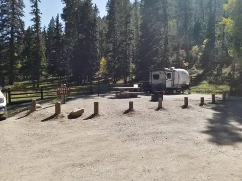 A camper occupies the host site at Panchulea with pines in the background.