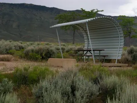 Picnic table with a shelter covering one side and over head.