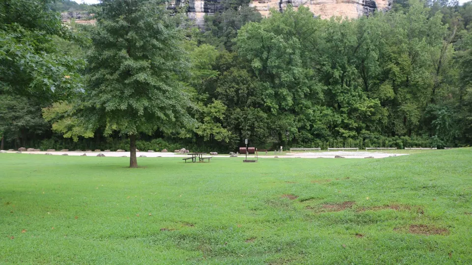 A sandstone bluff stands above the grassy campground.