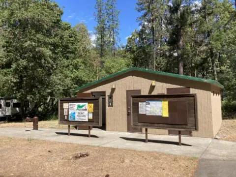 Tan building with green room and brown notice boards in front.