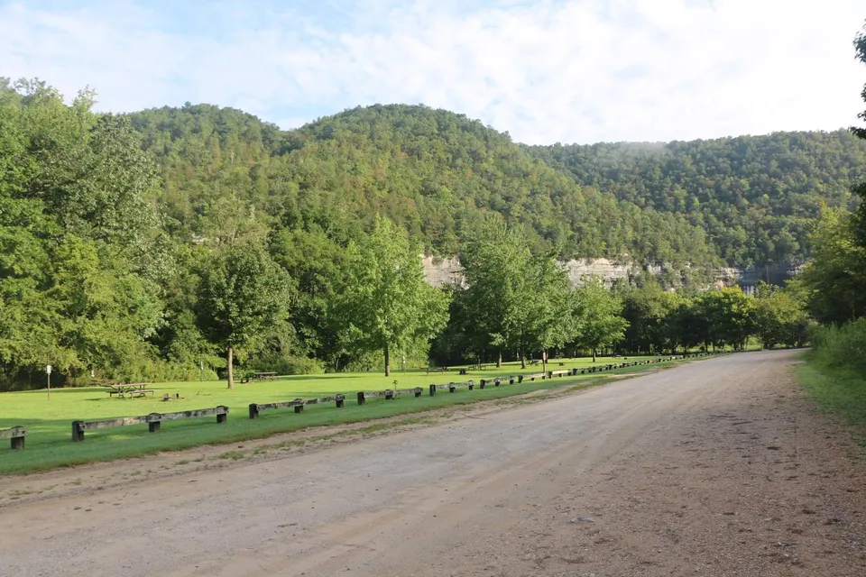 A dirt road can be seen on the right side of the photo with green grass and campsites on the left side.