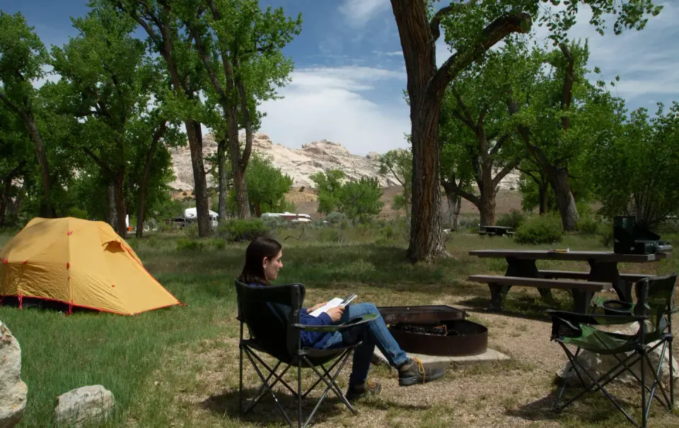 Camper relaxing in camp chair in campsite.