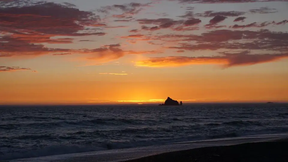 A sunset coloring an orange gradient in the sky at Rialto Beach.
