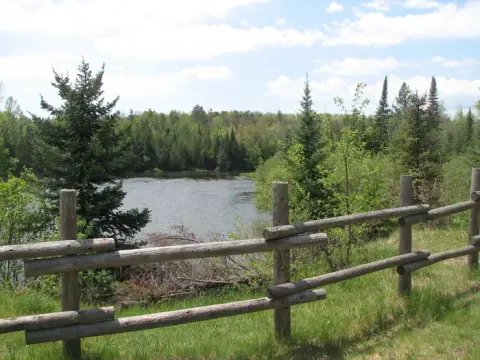 A view of the Au Sable River and a fence from the Au Sable Loop Day Use Area