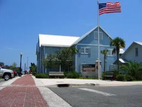 two story blue building along the waterfront with American flag flying
