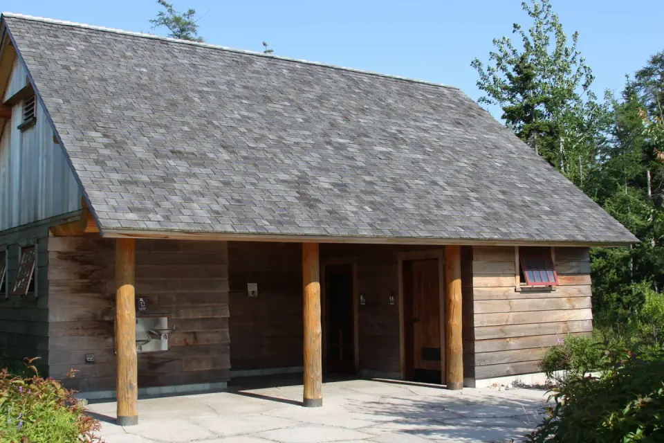 Wooden restroom building with water fountain and cedar siding.