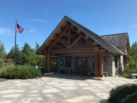 Log cabin style ranger station with the American flag flying on a blue sky day.