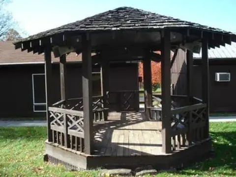 Small 9 foot wooden gazebo is located outside near the front door of the dining hall.
