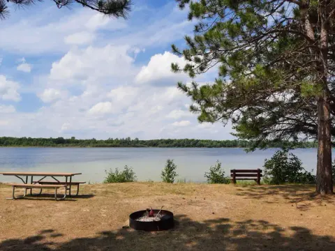 A picture of Mabel Lake with a firering, picnic table, and bench.