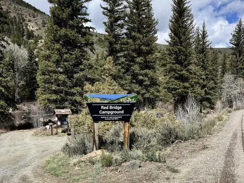 Forested rocky mountain terrain with sign "Red Bridge Campground"