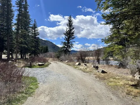 River next to gravel campground loop road, forested and rocky