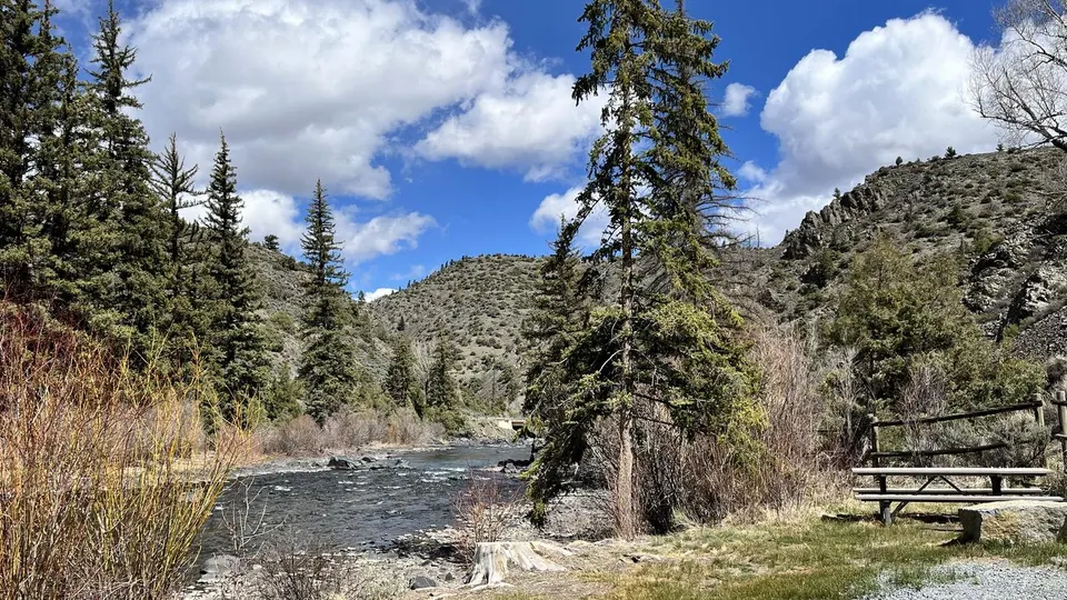 River through mountainous terrain, forested and rocky. Picnic table