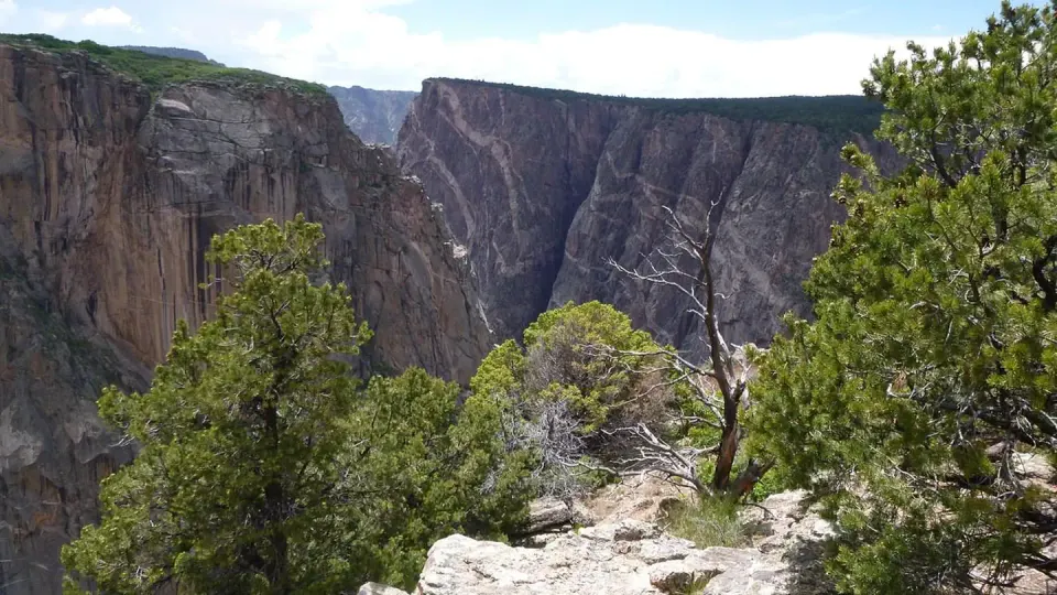 A view of the canyon from from Chasm View Nature Trail, framed by juniper and pinyon