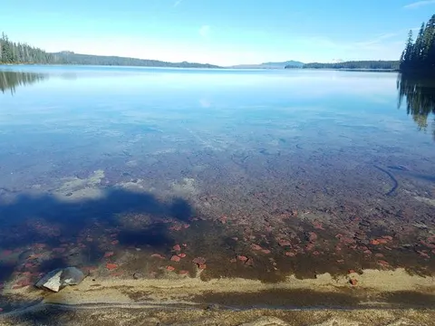 Clear Lake with stones, mountains and trees visible off in the distance.