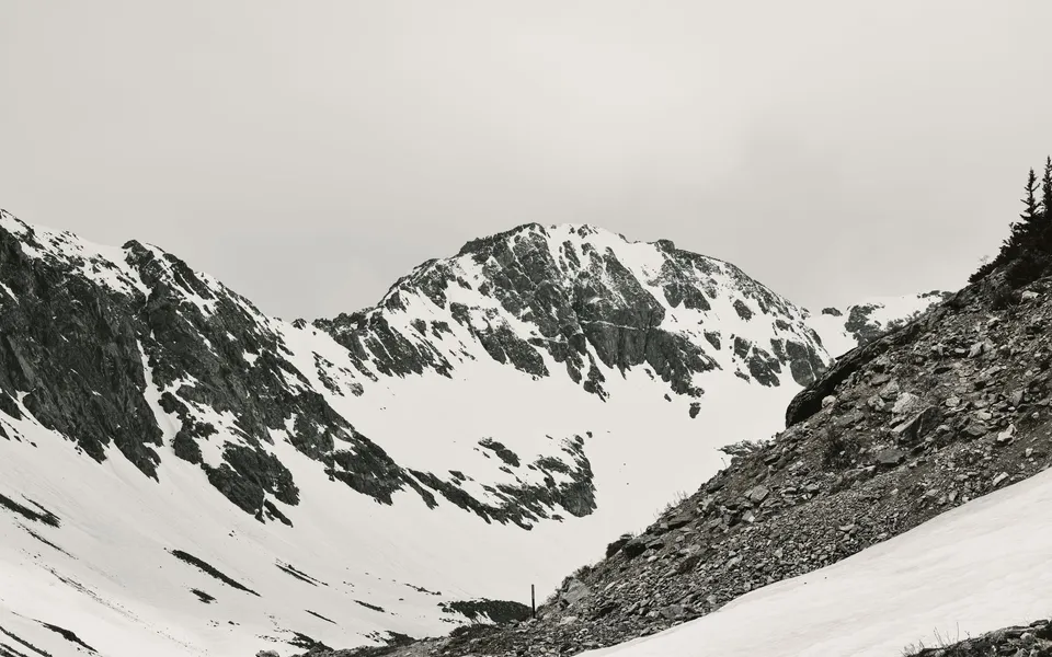 A serene black and white panorama of snow-covered rocky mountain slopes in Colorado.