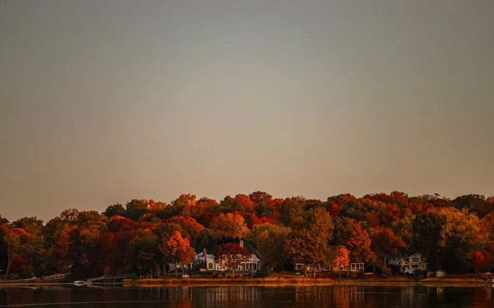 Serene autumn landscape with vibrant foliage reflecting in tranquil waters during sunrise in Stamford, Connecticut.