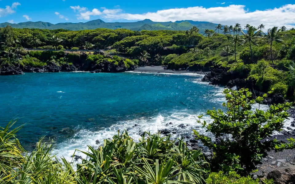 Explore the lush green landscapes and blue waters of Hana Bay, with its unique black sand beach and tropical flora.